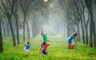 four boy playing ball on green grass