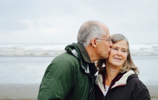 man kissing woman on check beside body of water